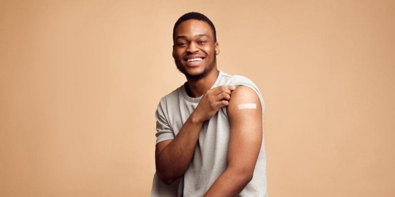 Covid-19,Vaccinated,African,Man,Showing,Arm,With,Plaster,,Beige,Background/